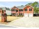 Two-story brick home featuring an attached two-car garage, landscaping, and large driveway at 3903 Cain Mill Dr, Lithonia, GA 30038