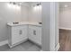 Corner bathroom vanity with double sinks, white cabinets, dark hardware, and tiled floors at 247 Old Timber Rd, Lawrenceville, GA 30046