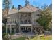 Elegant stone home featuring multiple balconies and a stone patio with outdoor seating and a fire pit at 6316 Woodlake Dr, Buford, GA 30518