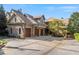 Stone home featuring a large driveway leading to a spacious three-car garage with wooden doors at 6316 Woodlake Dr, Buford, GA 30518