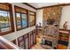 Spacious great room boasting a stone fireplace, built-in shelving, large windows with lake views and a ceiling fan at 6316 Woodlake Dr, Buford, GA 30518