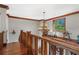 Upstairs hallway featuring hardwood floors, decorative trim, a chandelier and view to the outdoors through a window at 6316 Woodlake Dr, Buford, GA 30518