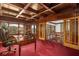 Elegant office with wood paneled walls, coffered ceiling, red carpet, and built-in bookshelves overlooking mature trees at 6316 Woodlake Dr, Buford, GA 30518