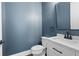 Modern half bathroom with blue walls, wood floors, white vanity, and a mirror at 319 Riverton Way, Woodstock, GA 30188