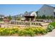 Welcoming entrance sign to Bluestone Park, surrounded by colorful flowers and lush greenery at 319 Riverton Way, Woodstock, GA 30188