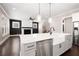 Bright, open concept kitchen with stainless steel appliances, farmhouse sink, kitchen island, and view to the living room at 319 Riverton Way, Woodstock, GA 30188