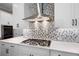 Close up of the kitchen with white cabinetry, mosaic tile backsplash, stainless vent hood, and a gas cooktop at 319 Riverton Way, Woodstock, GA 30188