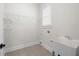 Clean and functional laundry room with wire shelving, tiled floor, utility sink and one window at 319 Riverton Way, Woodstock, GA 30188