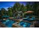 Twilight view of the backyard pool and hot tub, illuminated and surrounded by lush landscaping at 319 Riverton Way, Woodstock, GA 30188