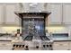 Close-up of a gourmet range with a decorative backsplash, stainless steel hood, and custom cabinetry at 2510 Bent Creek Way, Cumming, GA 30041