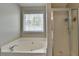 Corner bathtub and glass shower in an updated primary bath at 3285 Watson Gate Rd, Loganville, GA 30052