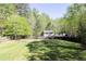 Large grassy backyard with a fire pit area and a wood fence surrounded by trees at 55 Maple Leaf Ct, Dallas, GA 30157