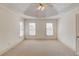 Spacious bedroom featuring neutral walls, neutral carpet and tray ceiling with fan at 5808 Deer Crossing Dr, Sugar Hill, GA 30518