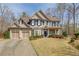 Charming two-story home featuring a manicured lawn, three-car garage, and inviting blue front door at 5808 Deer Crossing Dr, Sugar Hill, GA 30518