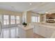 Open kitchen area features an island, breakfast bar, white cabinetry, tile flooring, and a clear view into the living room at 5808 Deer Crossing Dr, Sugar Hill, GA 30518