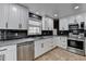 Updated kitchen features white cabinets, stainless steel appliances, granite countertops and black subway tile backsplash at 417 Wood Branch St, Woodstock, GA 30188