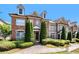 Exterior of brick townhomes with manicured landscaping, tall evergreens, and inviting entrances at 7620 Stoneridge Dr, Atlanta, GA 30328