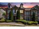 Townhome with brick facade, dormer windows, and professional landscaping at sunset at 7620 Stoneridge Dr, Atlanta, GA 30328