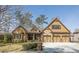 Inviting front exterior features a three-car garage, manicured lawn, and attractive mix of stone and siding accents at 2674 Hosanna Dr, Powder Springs, GA 30127