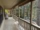 View of the back porch with wood floors, a railing, and a view of the wooded backyard at 302 Chattahoochee Way, Woodstock, GA 30188