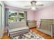 Cozy bedroom with a convertible sofa, crib, changing table, and a floral rug on hardwood floors at 3113 Octavia Pl, Atlanta, GA 30340