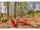Wooded backyard with a brick fire pit surrounded by red Adirondack chairs and a swing set at 3285 Pebble Ridge Ln, Buford, GA 30519