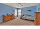 Blue bedroom with two windows, light-colored carpet, ceiling fan, and wood furniture at 3285 Pebble Ridge Ln, Buford, GA 30519