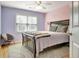 Cozy bedroom featuring light lavender walls, a bed, a window, and a chair at 155 Woodcreek Ln, Fayetteville, GA 30215
