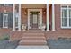 Inviting front porch with brick steps, white columns, and decorative flower pots at 155 Woodcreek Ln, Fayetteville, GA 30215