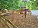 Community playground with slides, swings, picnic table, and playhouse, surrounded by trees and greenery at 155 Woodcreek Ln, Fayetteville, GA 30215