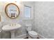 Elegant powder room featuring patterned wallpaper, pedestal sink, gold-framed mirror and natural light at 1130 Martins Chapel Rd, Lawrenceville, GA 30045