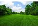 A large, well-maintained backyard with a lush green lawn surrounded by mature trees and blue sky at 2100 West Wesley Rd, Atlanta, GA 30327