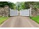 A stone and wood entrance gate leads to a private estate drive surrounded by mature trees at 2100 West Wesley Rd, Atlanta, GA 30327