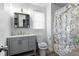 A bathroom featuring a vanity, a toilet, a shower with a white floral shower curtain, and gray wood floors at 3174 Country Club Nw Ct, Kennesaw, GA 30144