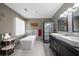 Modern bathroom featuring a soaking tub, glass-enclosed shower, double vanity, and stylish gray tiling at 3174 Country Club Nw Ct, Kennesaw, GA 30144
