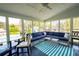 An enclosed porch with a ceiling fan, a blue sectional couch, and a glass top table overlooking the backyard at 3174 Country Club Nw Ct, Kennesaw, GA 30144