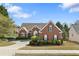 Charming brick home featuring a manicured lawn, mature trees, and a welcoming circular driveway at 3503 Dunbar Ln, Suwanee, GA 30024