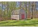 Backyard storage shed painted gray with red doors on a lawn surrounded by shady trees at 2806 Peachtree Walk, Duluth, GA 30096