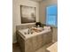 A soaking bathtub featuring tile surround, decor, and natural light through the window at 4569 Grenadine Cir, Acworth, GA 30101