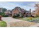 Stately brick home showcasing professionally landscaped grounds and an expansive driveway with stone accents at 5394 Brendlynn Dr, Suwanee, GA 30024