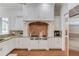 Spacious gourmet kitchen with white cabinets and a professional-grade gas range with custom hood at 5394 Brendlynn Dr, Suwanee, GA 30024