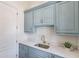 Laundry room with blue cabinets, white countertops and stainless steel sink at 5394 Brendlynn Dr, Suwanee, GA 30024