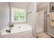 This bathroom offers a relaxing tub under a bright window and a separate shower with neutral tile surround at 1107 Fieldstone Dr, Canton, GA 30114