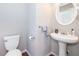 A half bathroom shows a pedestal sink with round mirror, with modern fixtures, and a convenient commode at 1107 Fieldstone Dr, Canton, GA 30114