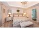 A neutral main bedroom offers a comfortable bed, a bench seat, and a view into the ensuite bathroom at 1107 Fieldstone Dr, Canton, GA 30114