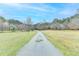 A winding driveway leads up to a lush green lawn surrounded by tall trees under a blue sky at 1880 Ridgedale Dr, Snellville, GA 30078