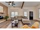 Open living room with a wood accent wall and shelf, hardwood floors, and neutral furniture under beamed ceiling at 1880 Ridgedale Dr, Snellville, GA 30078