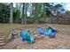 Backyard fire pit area featuring colorful chairs, a stone wall, and mature trees at 5215 Silver Creek Dr, Lilburn, GA 30047