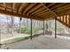 Spacious backyard with concrete under deck featuring green grass, trees, and bench in background at 1545 Smoke Hill Dr, Hoschton, GA 30548