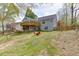 Exterior house view from backyard featuring wooden deck, porch, spacious grassy yard, and red chairs at 1545 Smoke Hill Dr, Hoschton, GA 30548